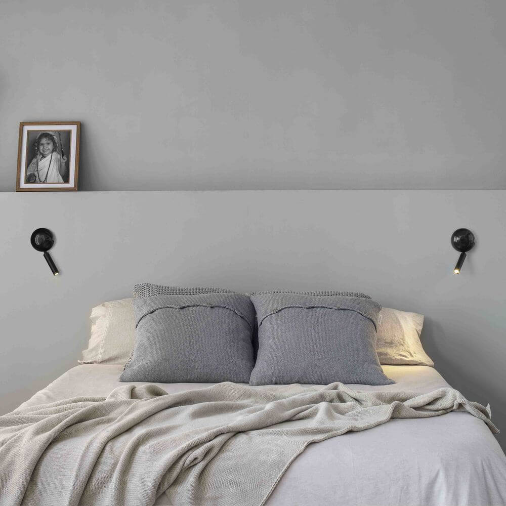 Press LED Wand-Leselampe über einem Bett mit Kissen und Decke in einem modernen Schlafzimmer.
