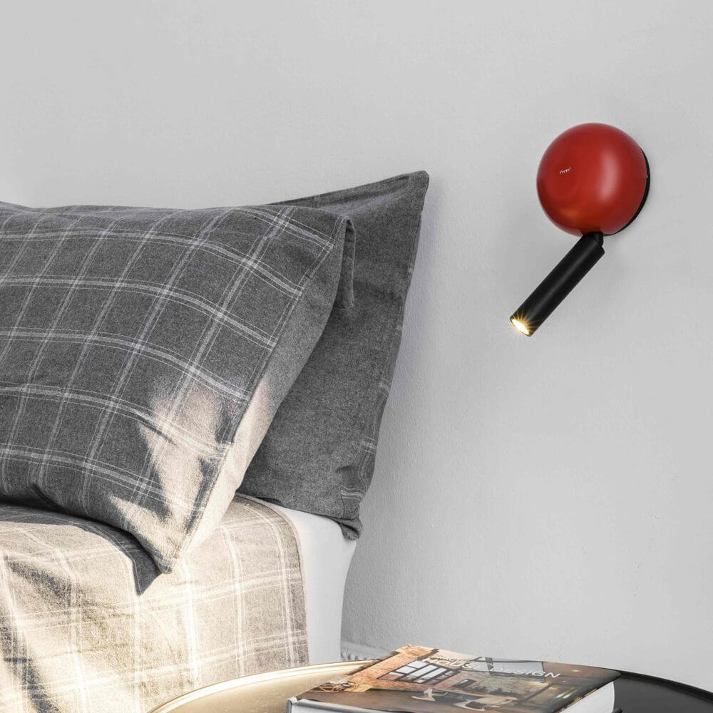 Press LED Wand-Leselampe an einer Wand über einem Bett mit Kissen und Decke.