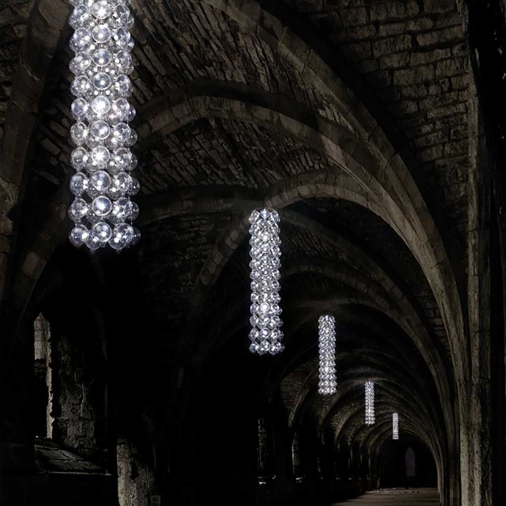 Hightower Design-Kronleuchter 40 in einem beeindruckenden, dunklen Gang mit hohen Bögen.