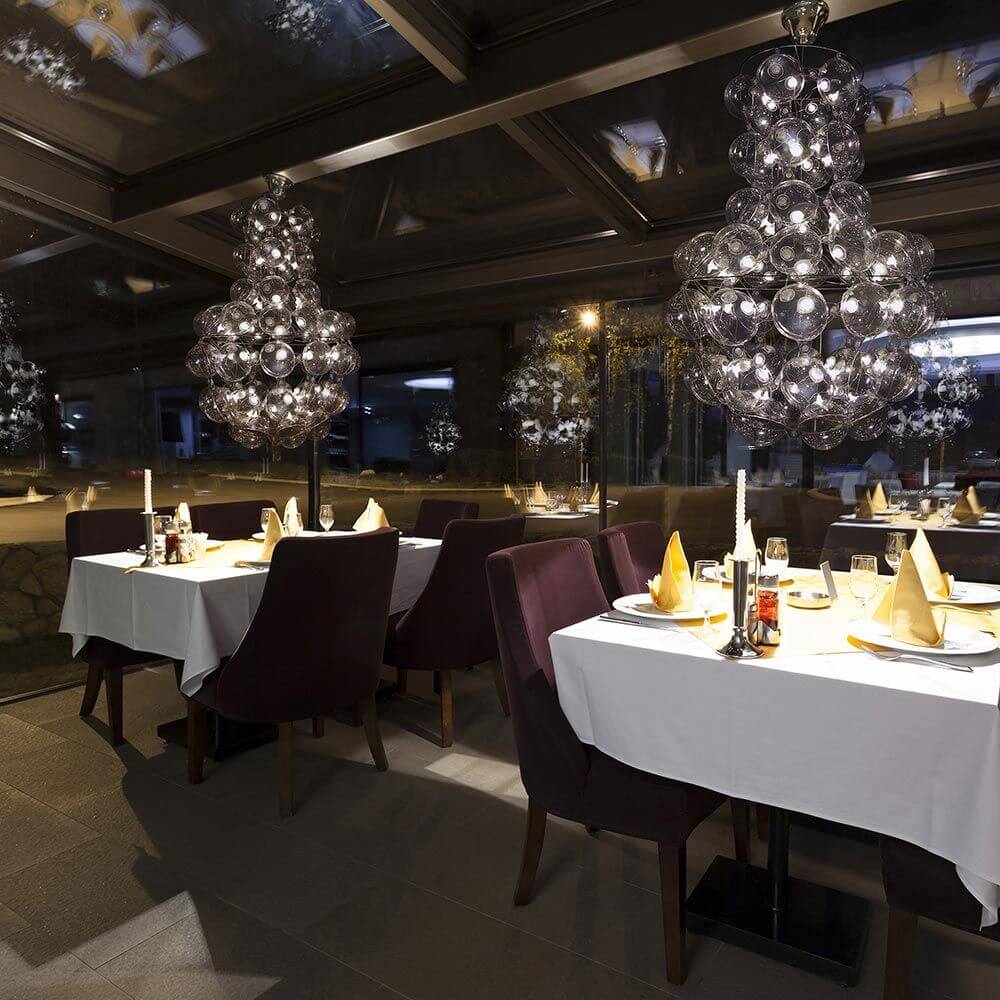 Prince's Design-Kronleuchter 65cm in stilvollem Restaurant mit eleganten Tischen und moderner Beleuchtung.