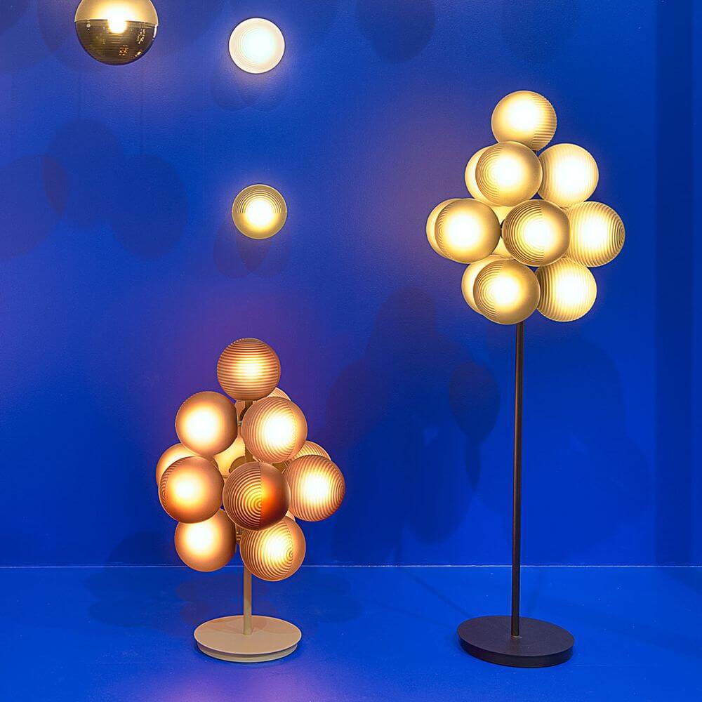 Pulpo LED Tischlampe Stellar Grape in Gold- und Beigetönen auf blauem Hintergrund, 13-globig.