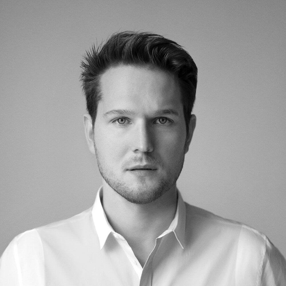 Schwarz-weiße Porträtaufnahme eines Mannes mit lässigem Hemd und ernstem Blick.