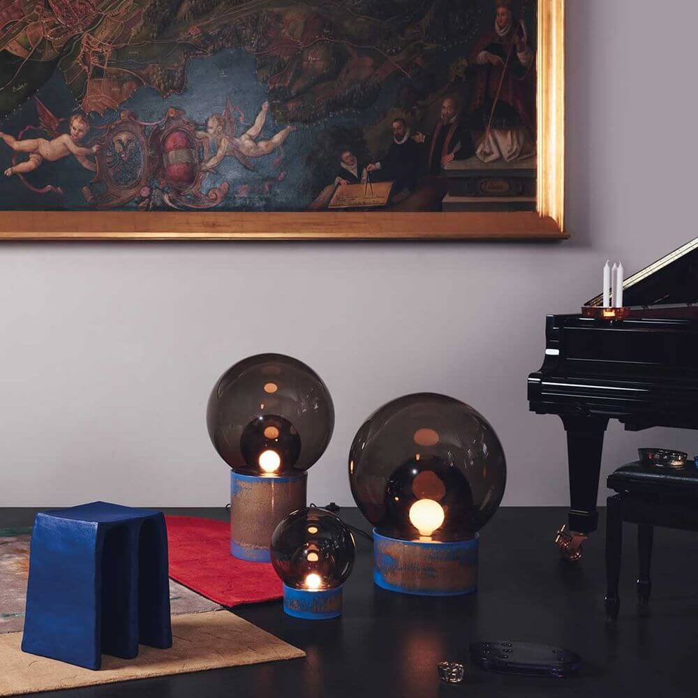 Pulpo Boule Tischlampen in verschiedenen Größen auf einem Tisch neben einem Klavier und Kunstwerk im Hintergrund.
