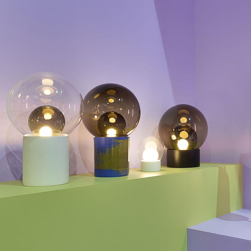 Pulpo Boule Tischlampen in verschiedenen Größen und Farben auf einem grünen Regal, stilvolle Beleuchtung für jeden Raum.