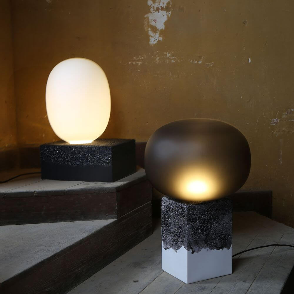 Pulpo LED Tischlampe Magma One in Schwarz und Weiß, mit sanftem Licht auf Treppen in rustikalem Ambiente.