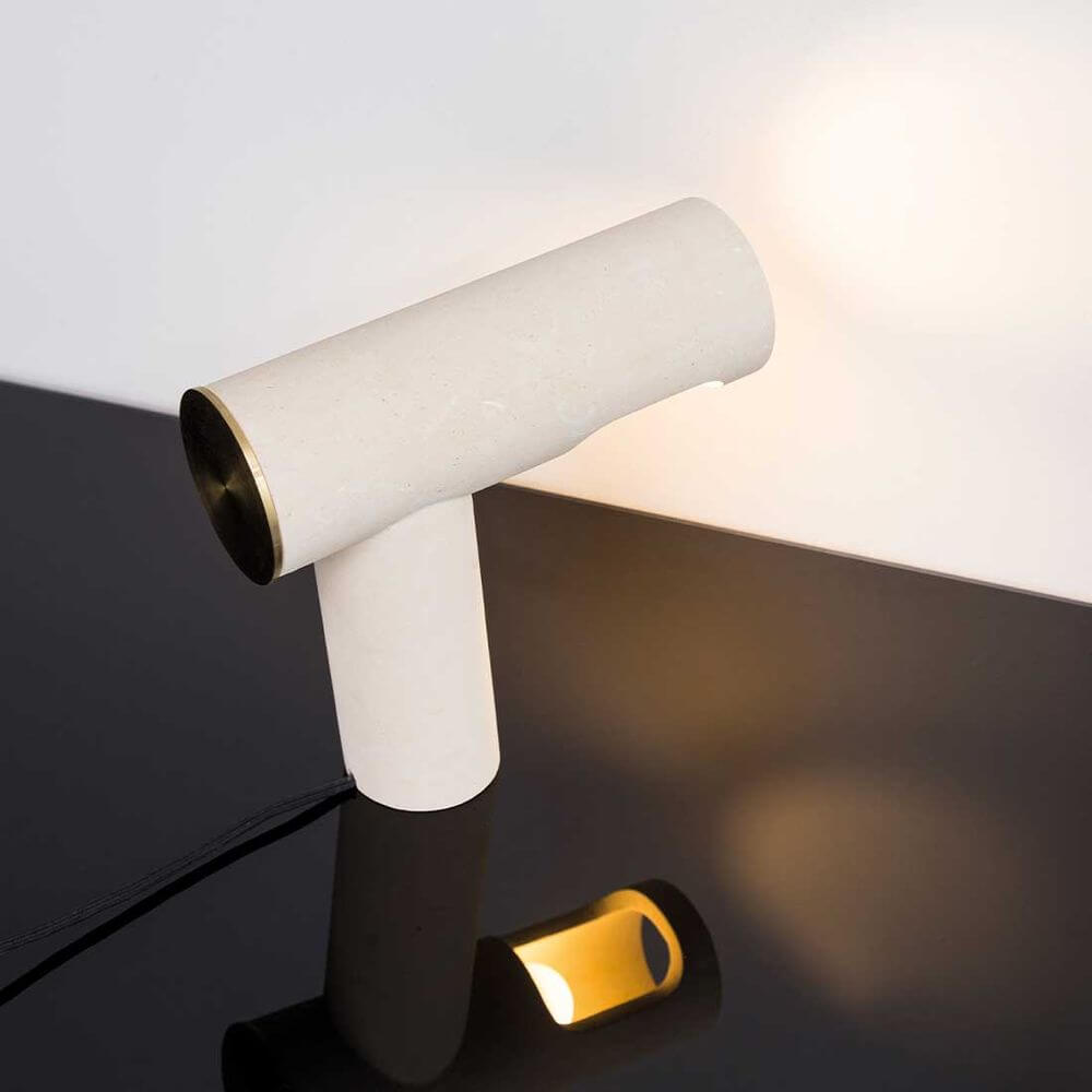 Pulpo LED Tischlampe aus Kalkstein mit goldener Umrandung auf schwarzem Tisch, modernes und elegantes Design.