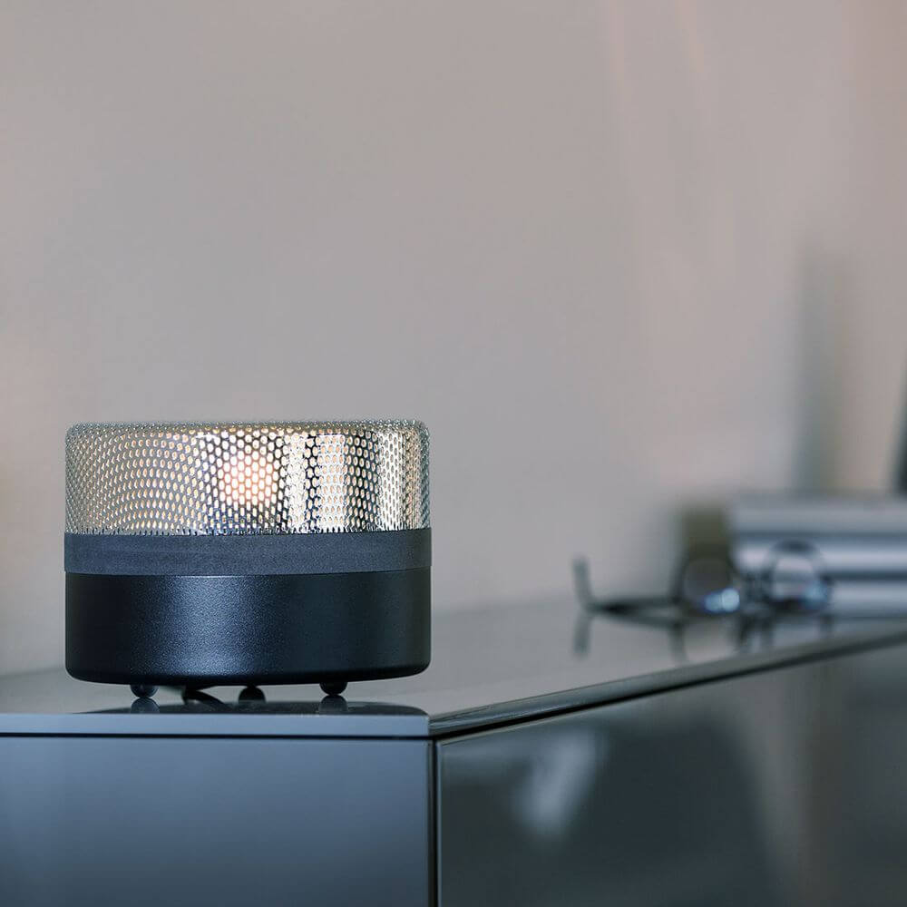 Pulpo LED Tischlampe Steel Drop Big auf einem Tisch, Lichtspiele durch Stahlschirm und schwarzem Sockel.