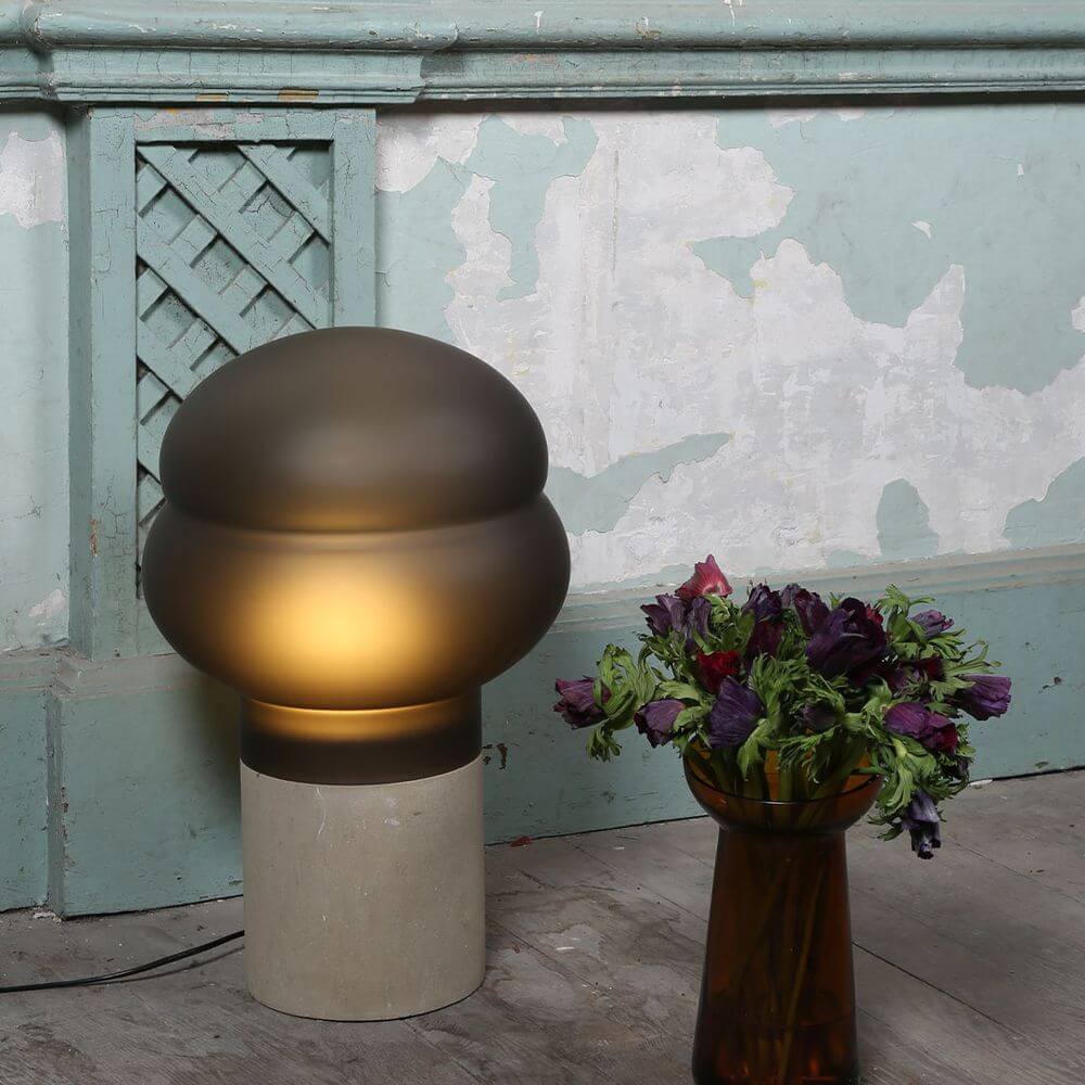 Kumo Tischleuchte mit moderner LED-Technologie, elegante Form auf grauem Sockel, harmonische Raumbeleuchtung