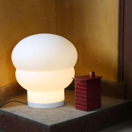Pulp LED Bordlampe Kumo Medium Ø 42cm ved siden af en dekorativ genstand på et bord.