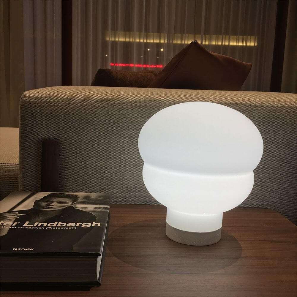 Moderne Pulpo LED Tischleuchte Kumo Medium Ø 42cm auf einem Beistelltisch, neben einem Buch.