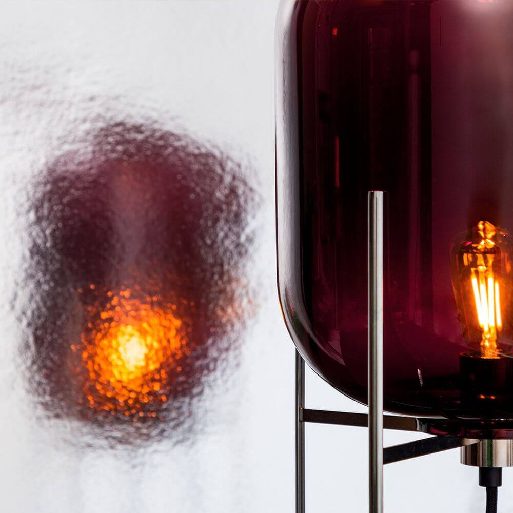 Pulpo LED Tischleuchte Oda Small in rot mit warmem Licht auf einem modernen Tisch, industrielles Design.