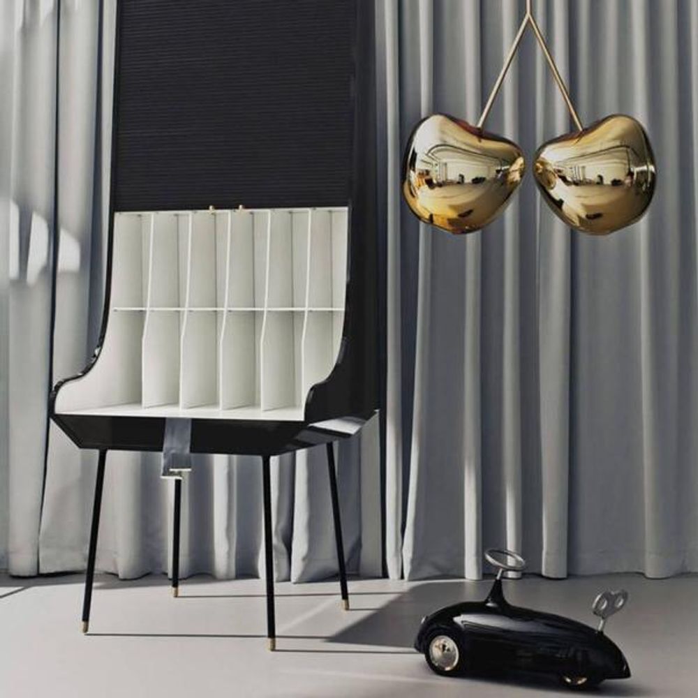 Cherry Lamp Metall Pendelleuchte Kirsche hängt über einem modernen Stuhl und einem Kinderspielzeugauto.