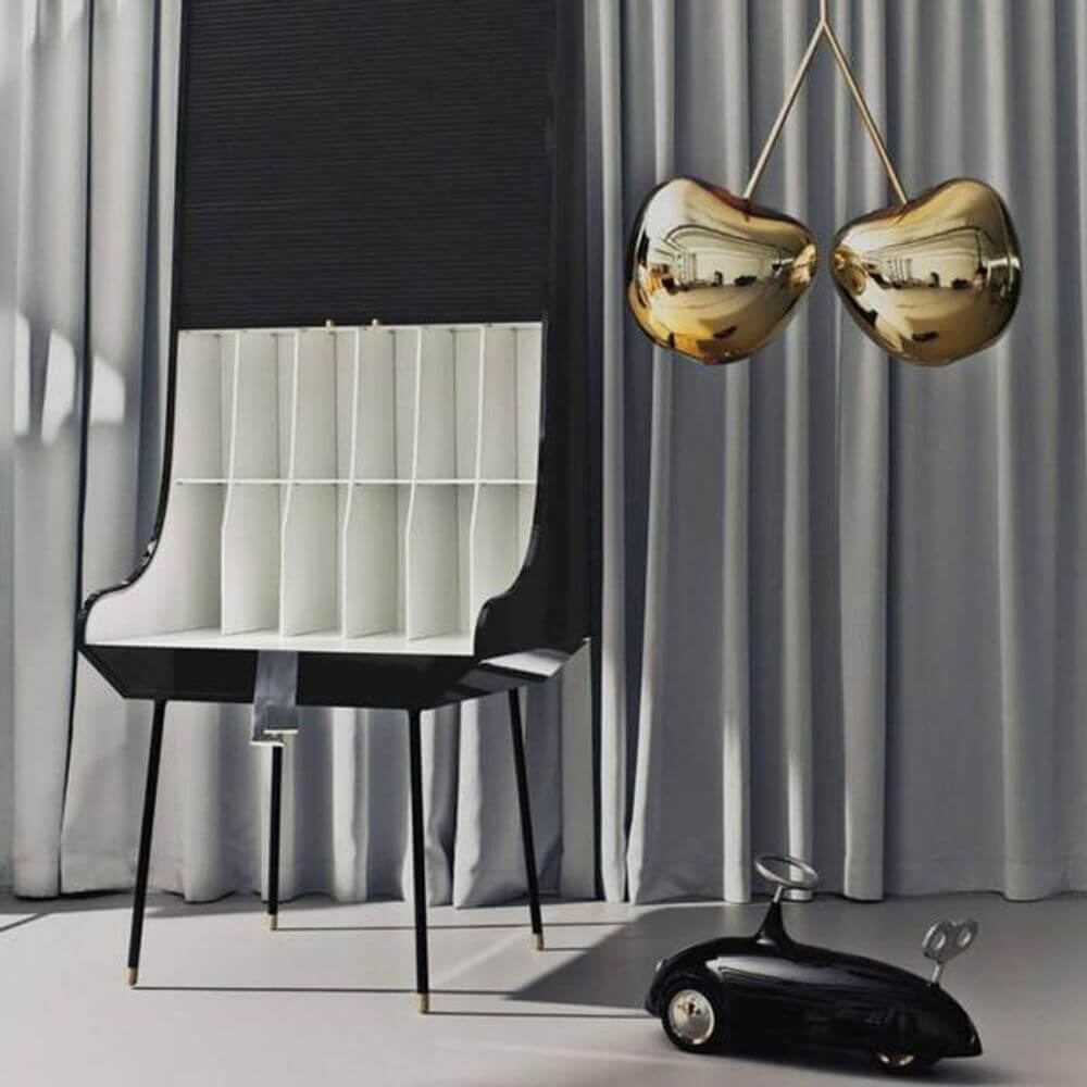 Cherry Lamp Metall Pendelleuchte Kirsche hängt über einem modernen Stuhl und einem Kinderspielzeugauto.
