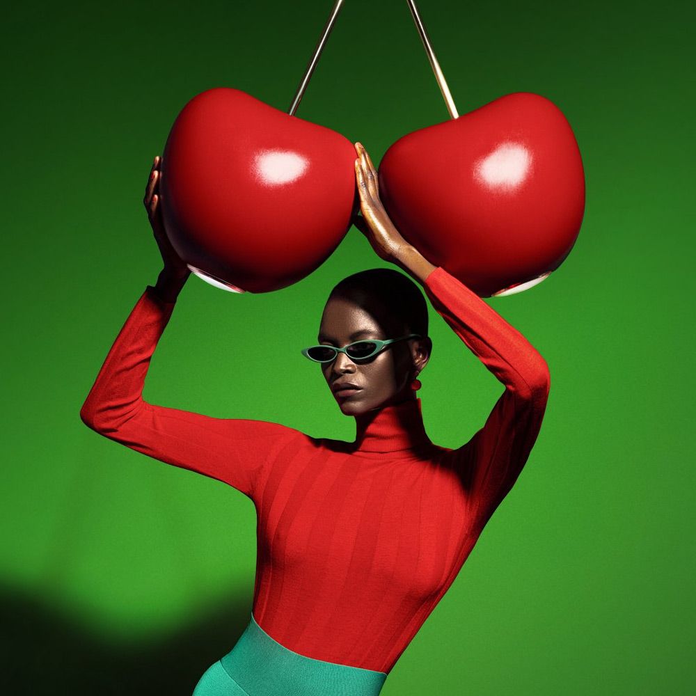 Cherry Lamp Pendelleuchte Kirsche, stylische Frau mit rotem Top und Sonnenbrille, die die Lampe hält.