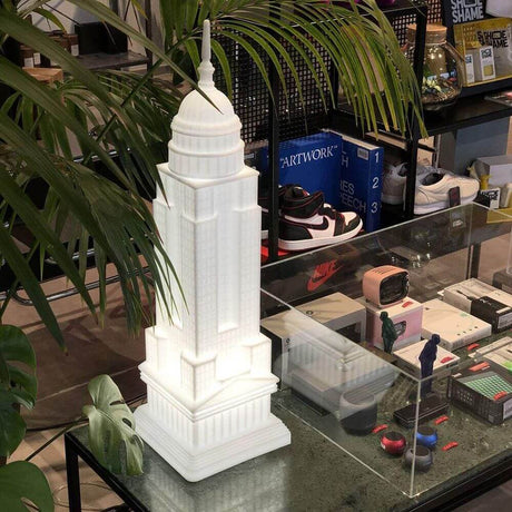 Empire table lamp in the shape of the Empire State Building on a table with plants and accessories.