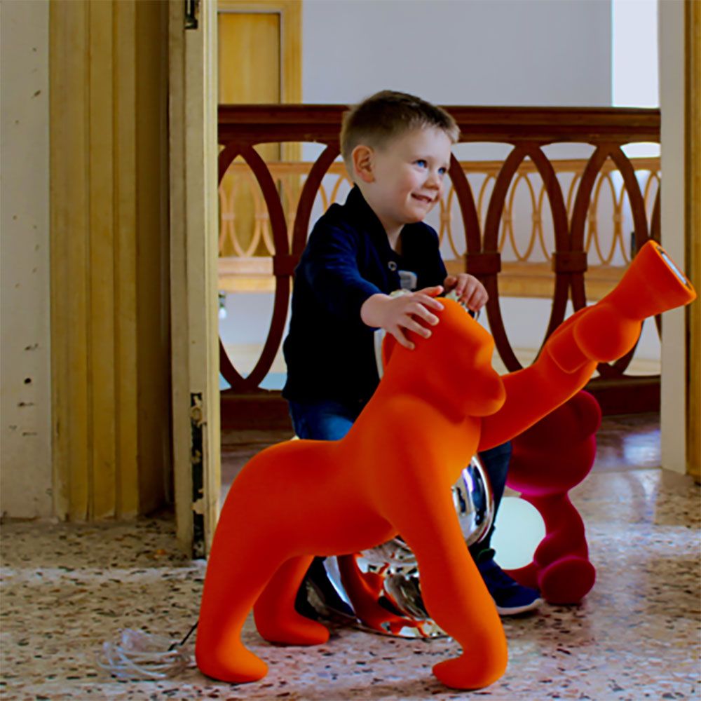Kong XS Samt Tischlampe Gorilla in orange, spielendes Kind im Innenraum.
