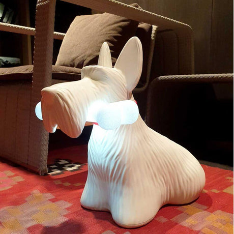 Scottie LED rechargeable floor lamp dog in the shape of a dog holding a bone in its hand on a colorful rug.