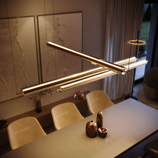 Moderne Pendelleuchte über einem Esstisch in einem stilvollen Raum mit hellen Stühlen und dekorativen Elementen.