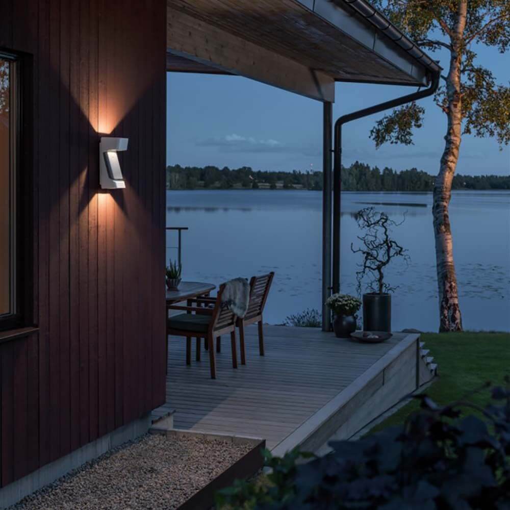 Ravenna LED Wandleuchte IP54 installiert an einer modernen Hauswand mit Blick auf den See bei Dämmerung.