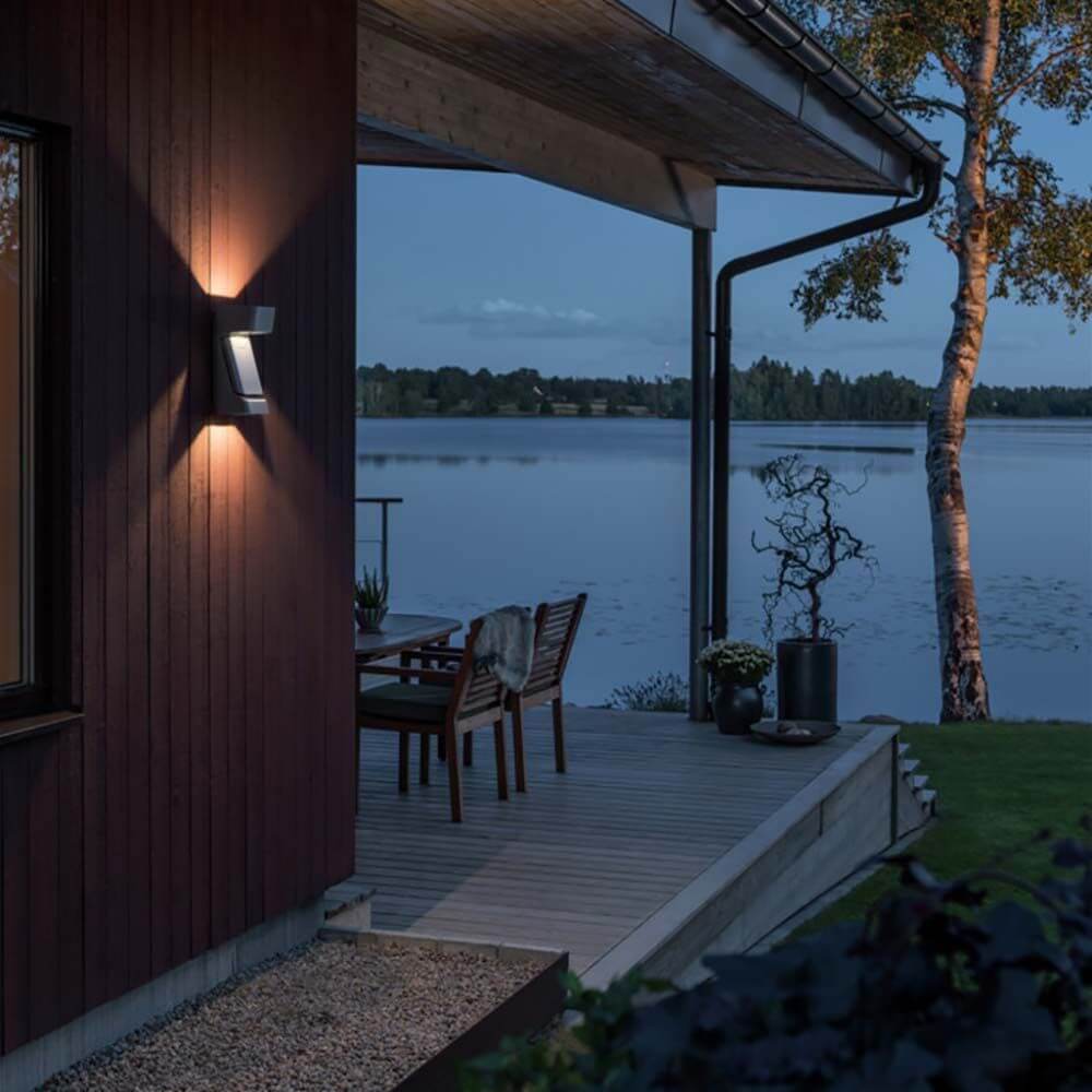 Ravenna LED Wandleuchte IP54 an einer Wand mit Blick auf einen See bei Dämmerung.