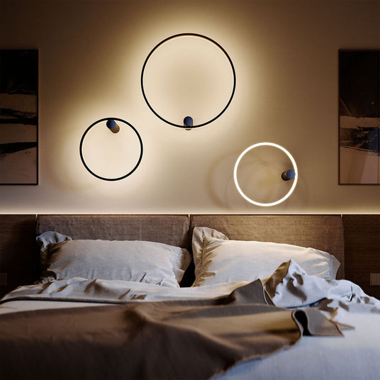 Moderne Wandleuchten in Kreisform über einem stilvollen Bett, erzeugen ein sanftes Ambiente im Schlafzimmer.
