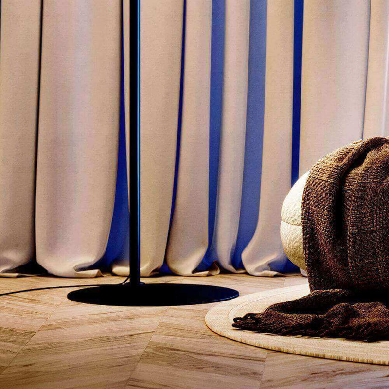 Moderne Stehlampe neben sanften Vorhängen und einem gemütlichen Teppich in warmem Licht.