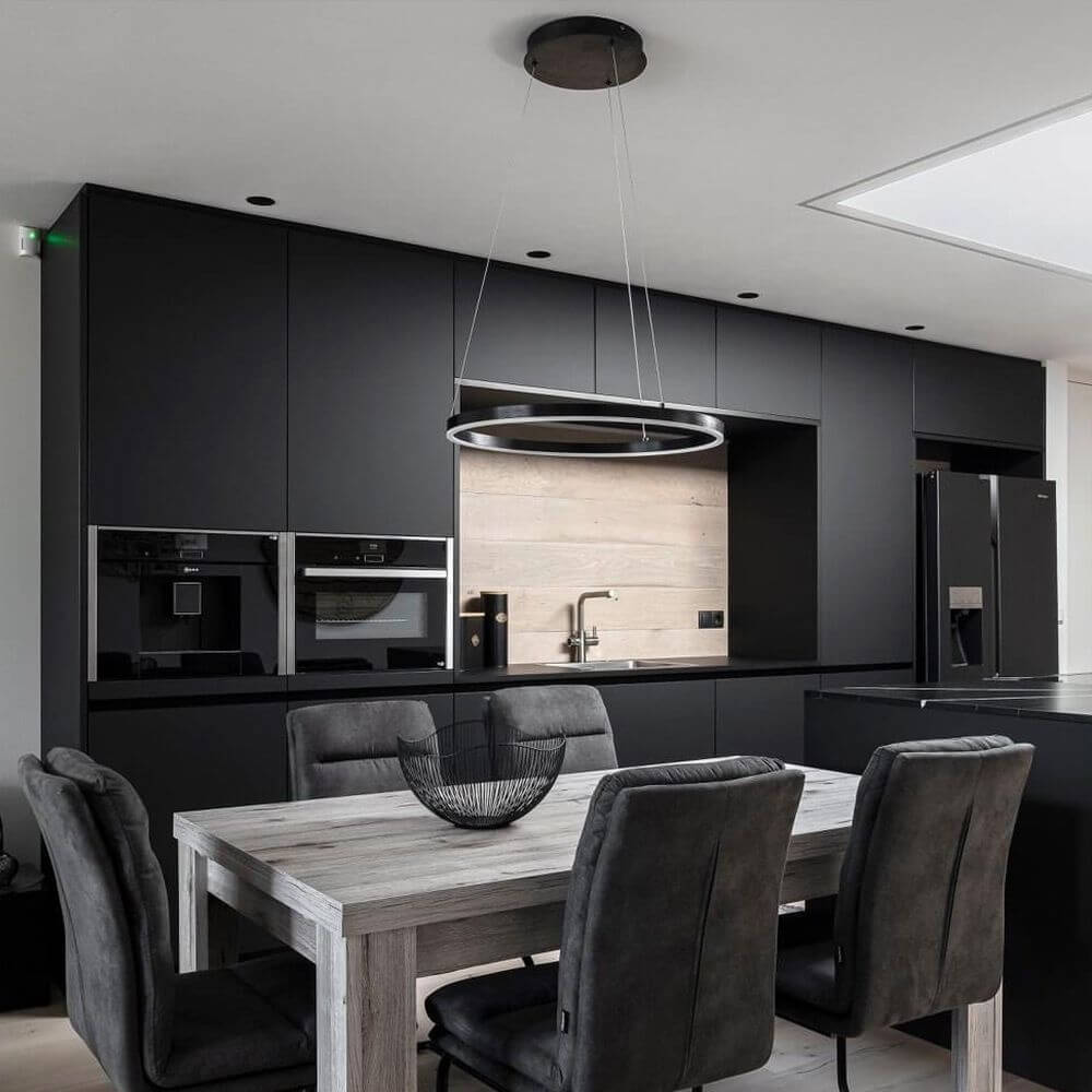 Moderne schwarze Küche mit s.luce Ring Hängeleuchte über dem Holztisch.