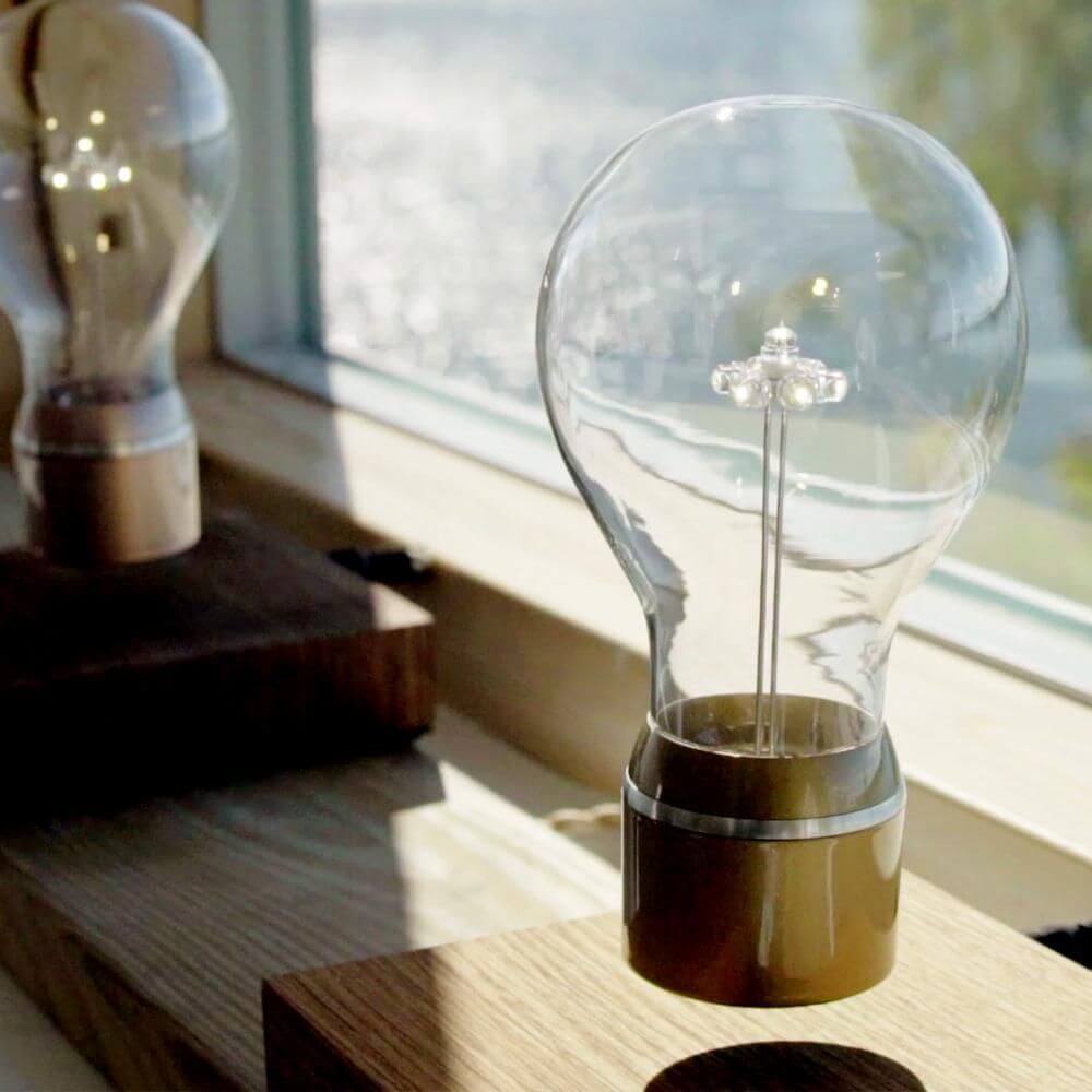 LED-Dekotischleuchte schwebende Glühbirne elegant mit transparentem Glaskörper auf Holzsockel.