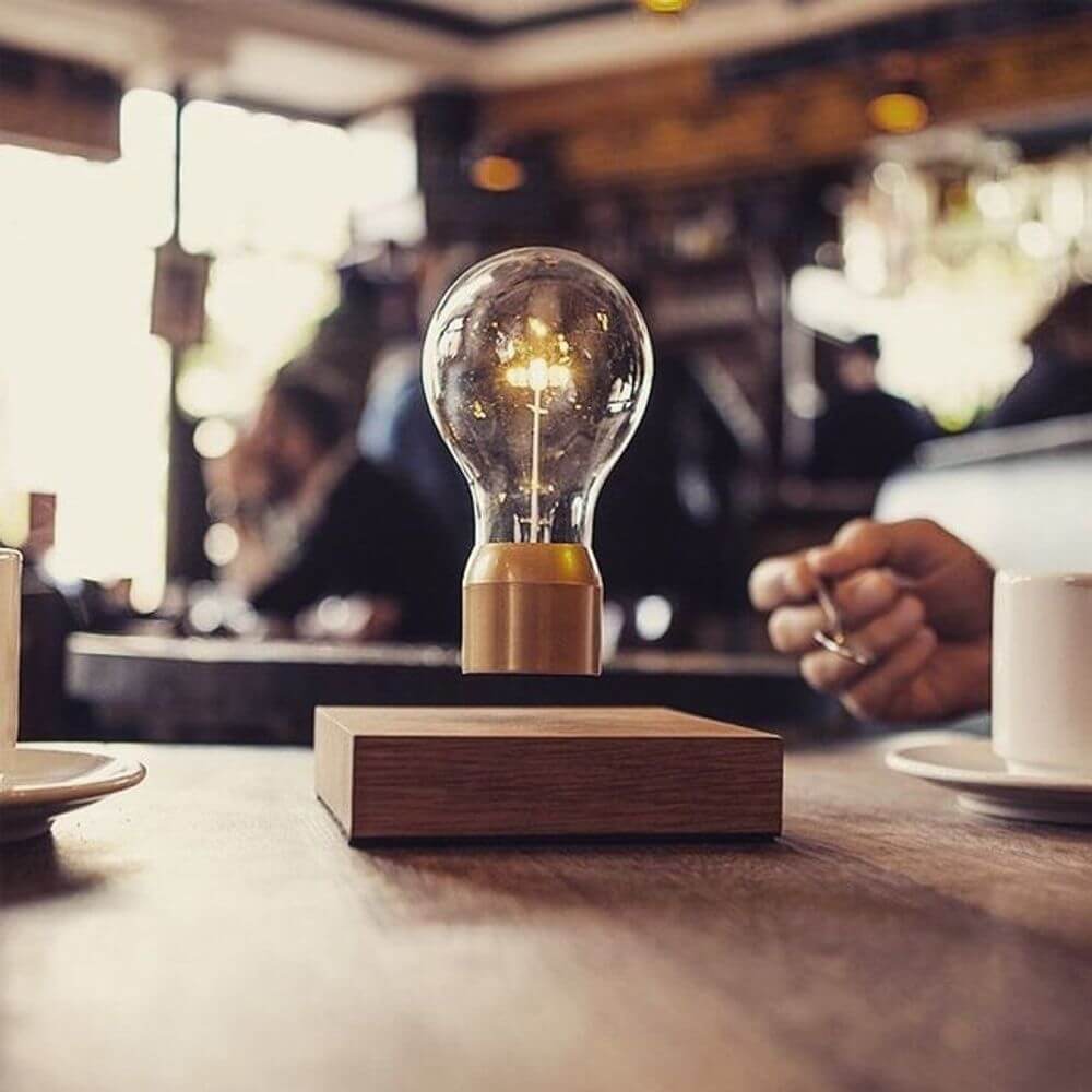LED-Dekotischleuchte schwebende Glühbirne auf einem Tisch in einem Café mit elegantem Design.