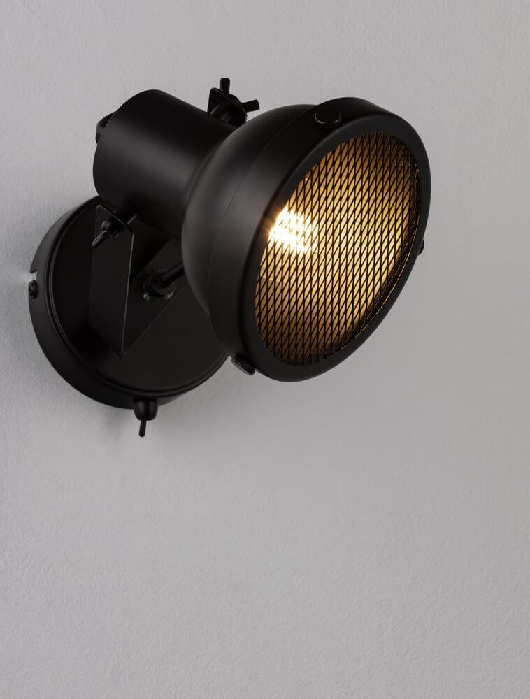 Ruvi Wandleuchte Schwarz an der Wand mit industriellem Design und kontrastvollem Licht.