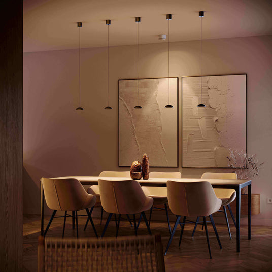 Modernes Esszimmer mit stilvollen Pendelleuchten und minimalistischer Kunst an der Wand.