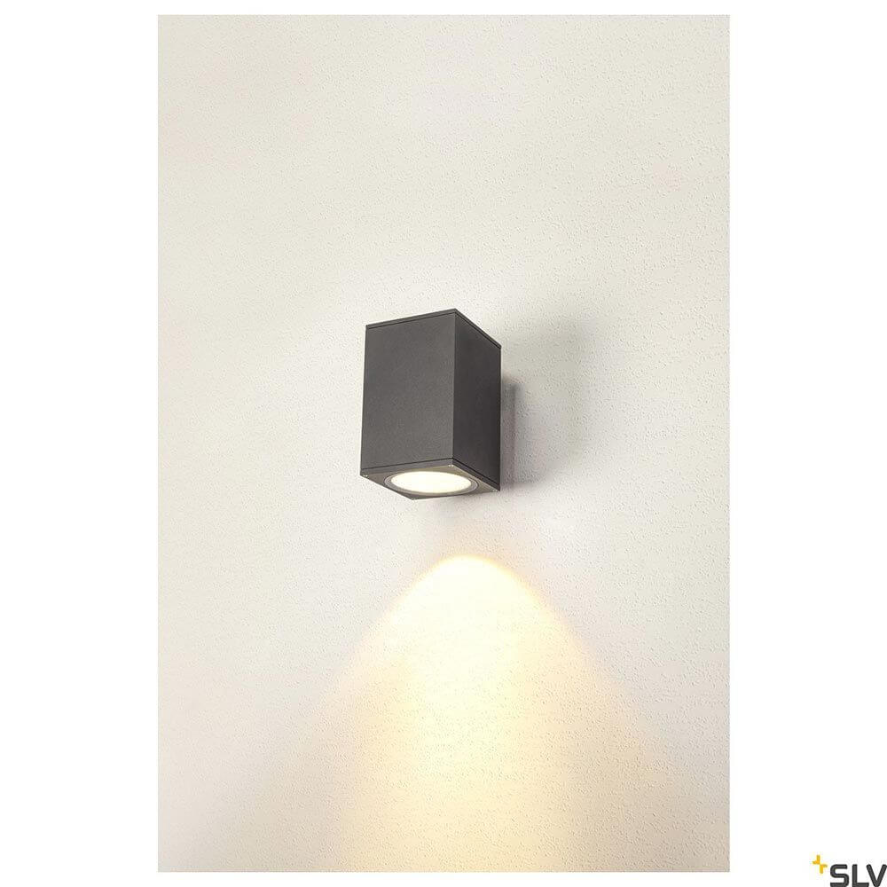 Enola LED Wandaufbauleuchte Square IP65 Anthrazit an Wand, quadratisches Design mit warmem Lichtschein.