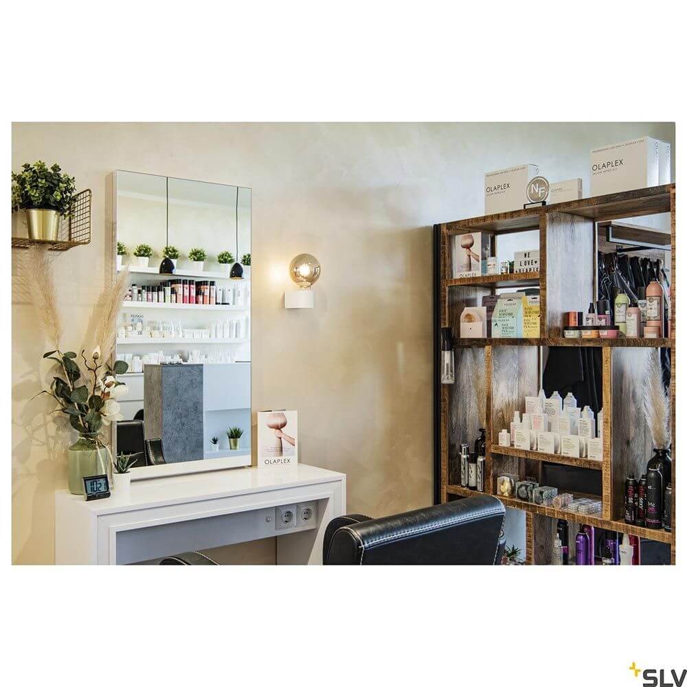 Fitu Cube Wandleuchte in stylischem Salon mit Spiegel und Regalen für Pflegeprodukte.