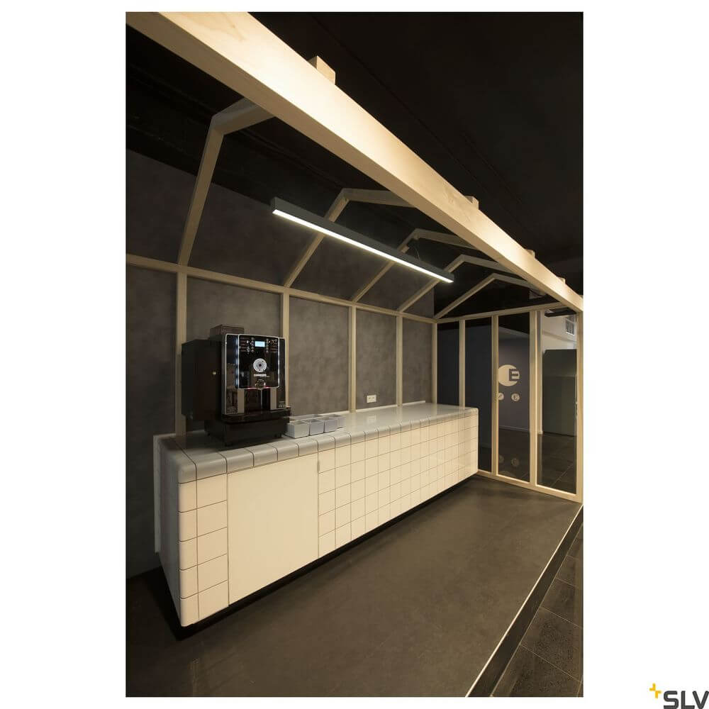 Moderne Pendellampe im Schwarz über einer minimalistischen Bar in einem eleganten Raum.