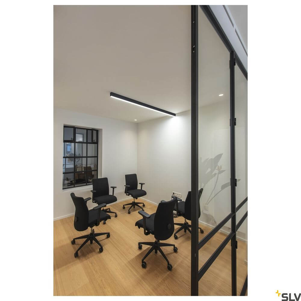 Moderne Pendellampe in einem Büroumfeld mit schwarzen Bürostühlen und natürlichem Licht.