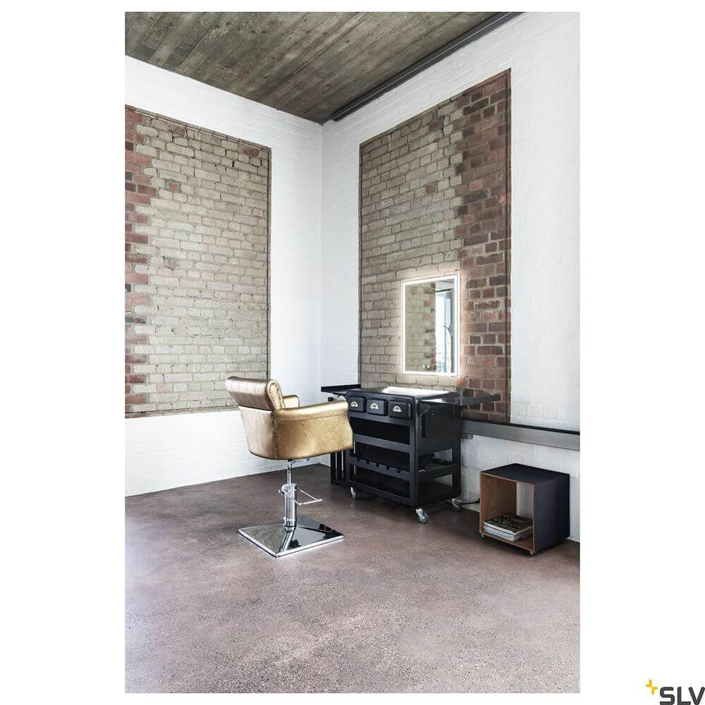 Helle Friseurecke mit goldfarbigem Friseurstuhl und großer Spiegelkante in einem modernen Raum.