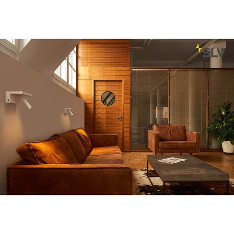 Karpo Bedside LED applique murale blanc dans un intérieur moderne avec canapé et détails en bois.