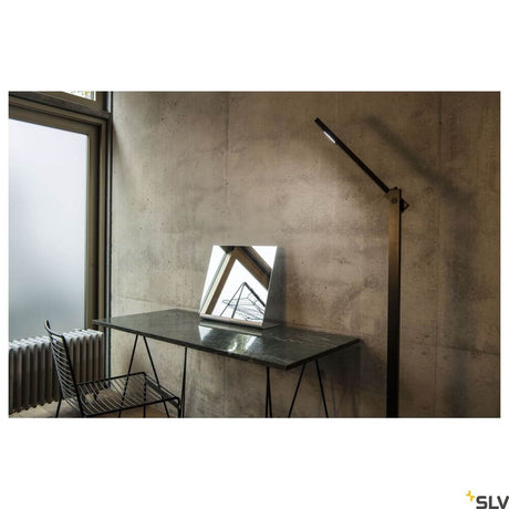 Mecanica Plus FL kontorgulvlampe 2700-6500K svart ved siden av et moderne skrivebord med speil.