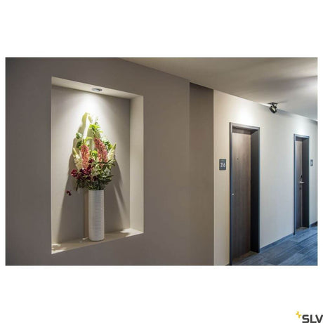 New Tria 68 I Cs ceiling light Alu 2700K Round illuminates a flower vase in the hallway.