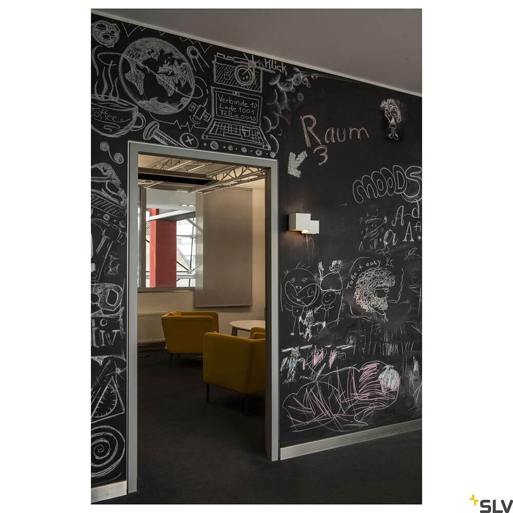 Plastra Cubes Wandleuchte Weiß in modernem Raum mit Kreidetafel-Wänden und gelben Sesseln.