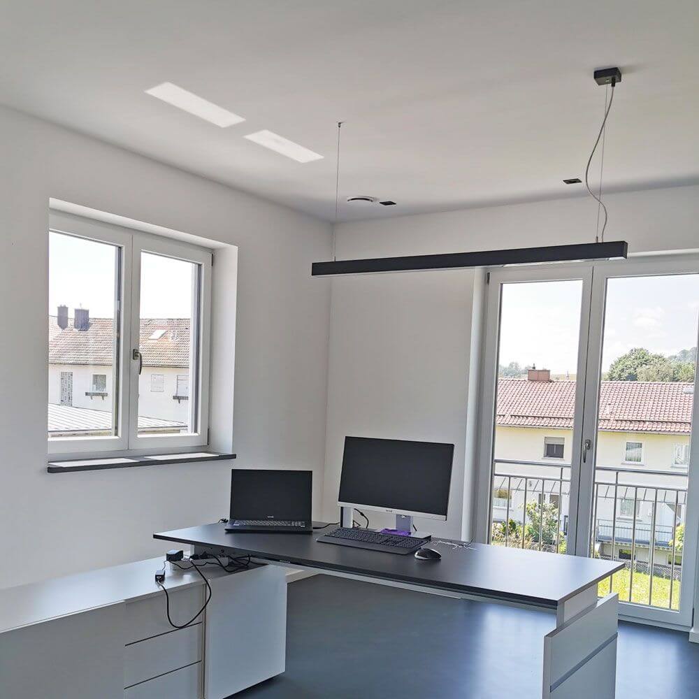 Moderne Büroeinrichtung mit Q-Line Dali Pendelleuchte in Schwarz und zwei Monitoren.