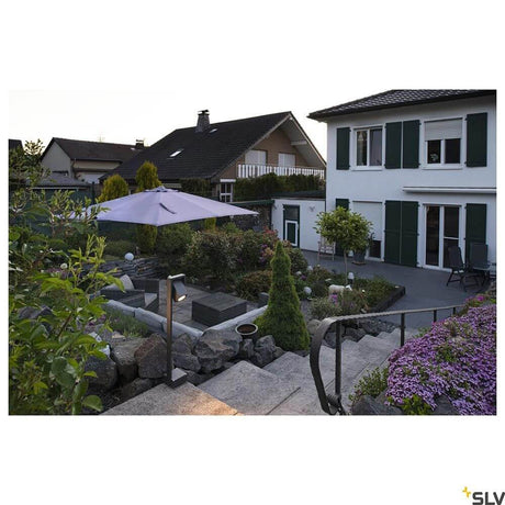 Lampadaire d’extérieur Theo Bracket Anthracite IP65 dans le jardin avec parasol et plantations élégantes.