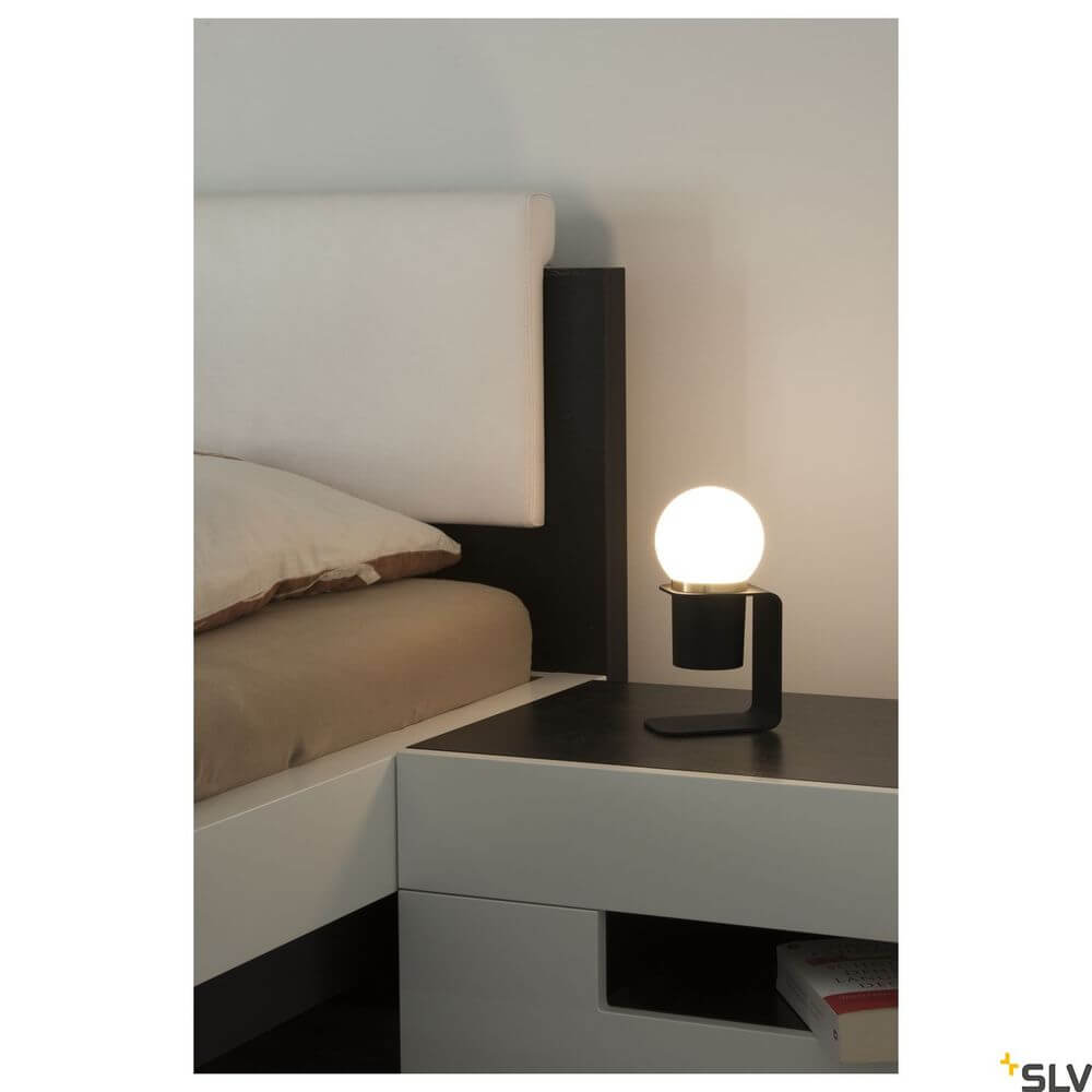 Tonila Mobile Akku-Tischleuchte Schwarz auf Nachttisch neben Bett, warmes Licht für gemütliche Atmosphäre.