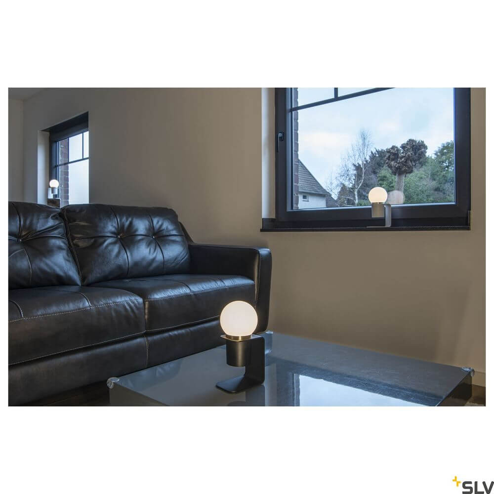 Tonila Mobile Akku-Tischleuchte Schwarz im Wohnzimmer neben einem Fenster auf einem Tisch.