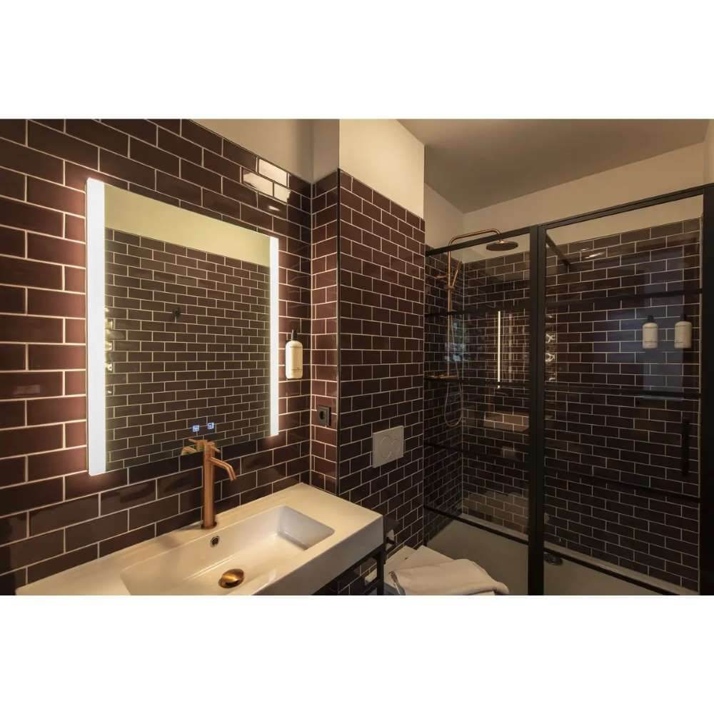 Modernes Badezimmer mit dimmbarer Trukko Square LED Spiegel-Wandleuchte und stilvollen Fliesen.