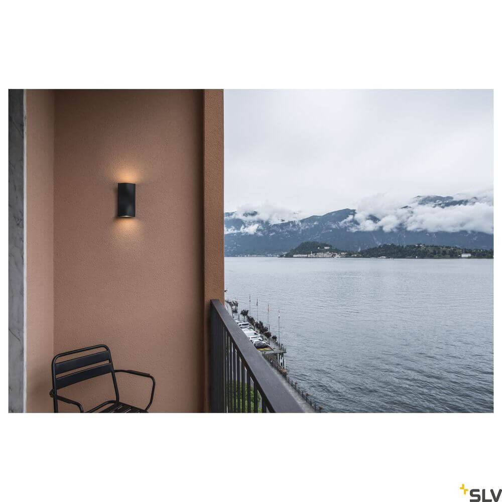 Vilua Up & Down Außen-Wandlampe LED Anthrazit IP54 an einer Wand mit Blick auf den See.