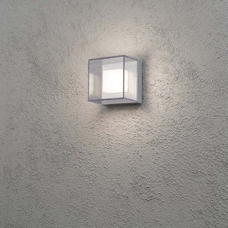 Lampa ścienna LED Sanremo w kolorze szarym zamontowana na strukturalnej ścianie, emitująca jasne światło.