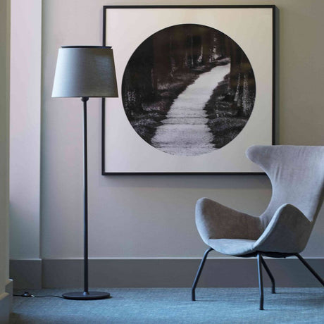 Savoy Stehlampe 160cm (ohne Schirm) neben einem grauen Sessel und einem Kunstwerk an der Wand.