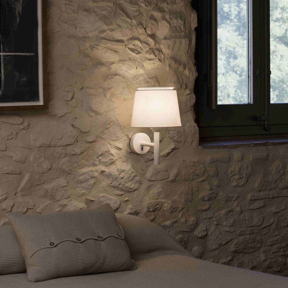 Savoy Wandlampe (ohne Schirm) an einer steinernen Wand im Schlafzimmer, strahlt sanftes Licht aus.