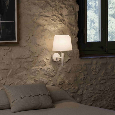 Savoy vegglampe (uten skjerm) på en steinvegg på soverommet, avgir mykt lys.